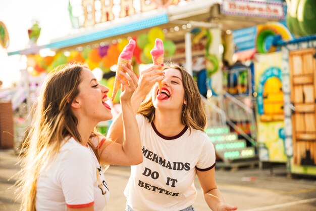 Zwei Freundinnen, die Eiscreme am Vergnügungspark essen