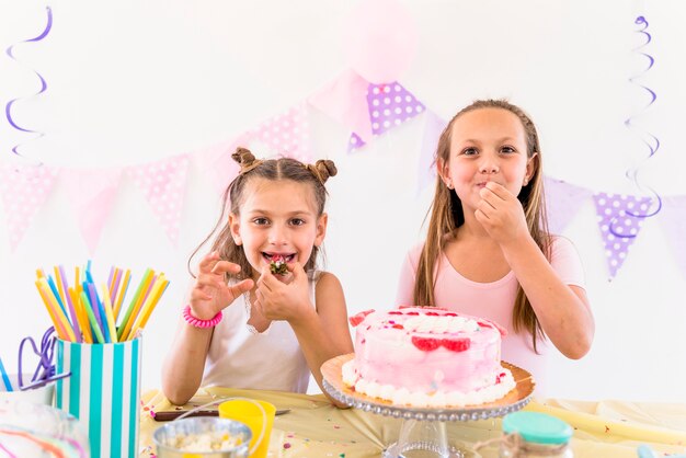Zwei Freundinnen, die Kuchen beim Genießen in der Geburtstagsfeier essen