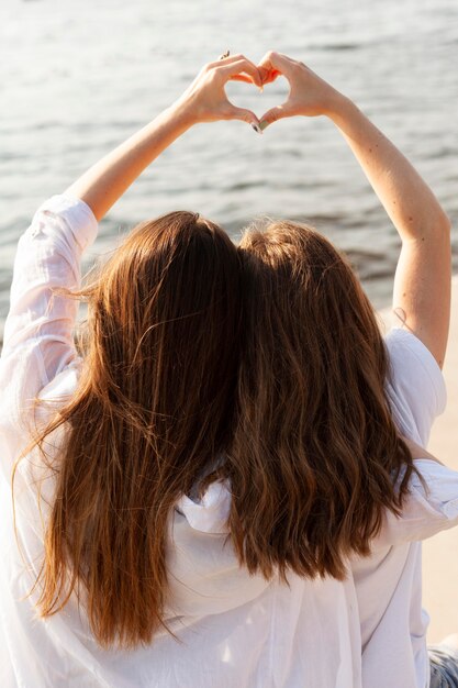 Zwei Freundinnen machen das Liebeszeichen am See