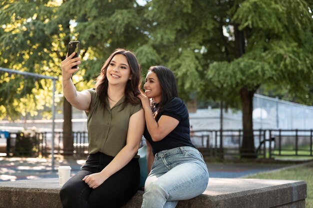 Zwei Freundinnen machen Selfie im Park, während sie einen Kaffee trinken