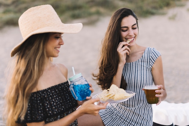 Zwei Freundinnen mit Getränken am Strand