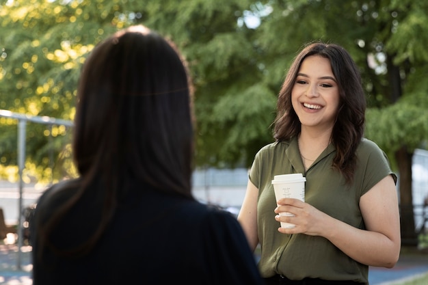 Zwei Freundinnen trinken gemeinsam eine Tasse Kaffee im Park