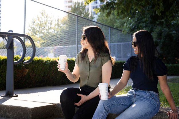 Zwei Freundinnen trinken gemeinsam eine Tasse Kaffee im Park