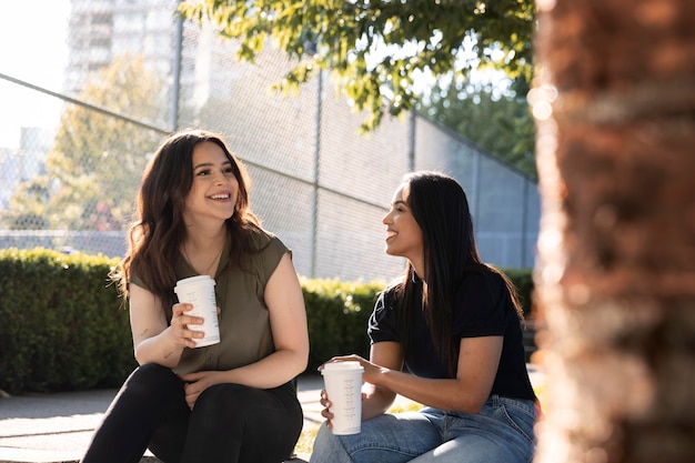 Zwei Freundinnen trinken gemeinsam eine Tasse Kaffee im Park