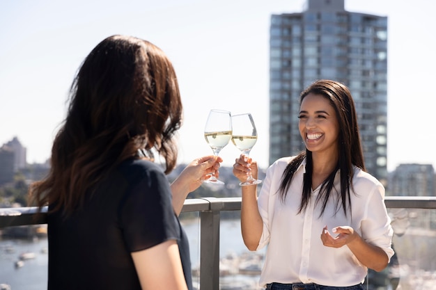 Kostenloses Foto zwei freundinnen unterhalten sich und genießen wein auf einer dachterrasse