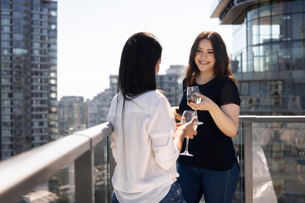 Zwei Freundinnen unterhalten sich und genießen Wein auf einer Dachterrasse