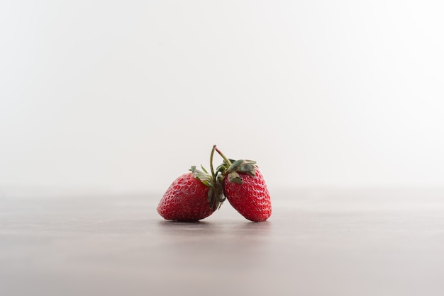Zwei frische Erdbeeren auf Marmortisch.