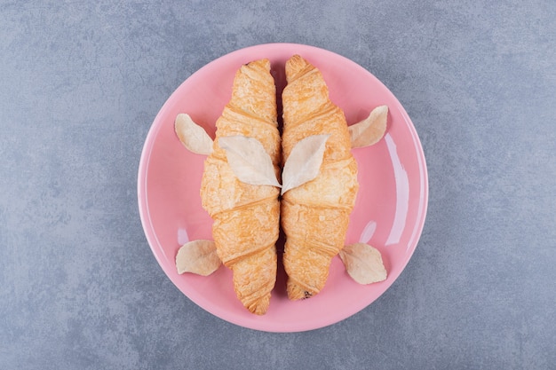 Zwei frische französische Croissants auf rosa Teller