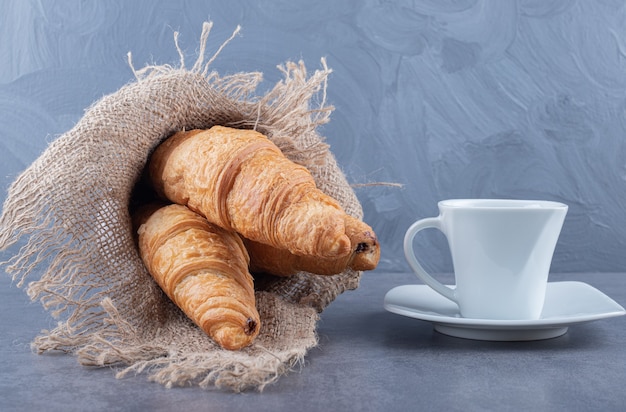 Kostenloses Foto zwei frische französische croissants mit kaffee auf grauem hintergrund.