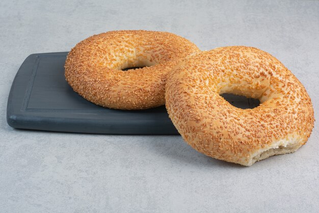 Zwei frische leckere Bagels auf dunklem Teller.