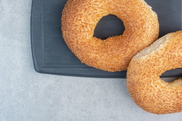 Zwei frische leckere Bagels auf dunklem Teller.