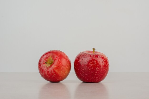 Zwei frische, rote Äpfel auf weißem Hintergrund.