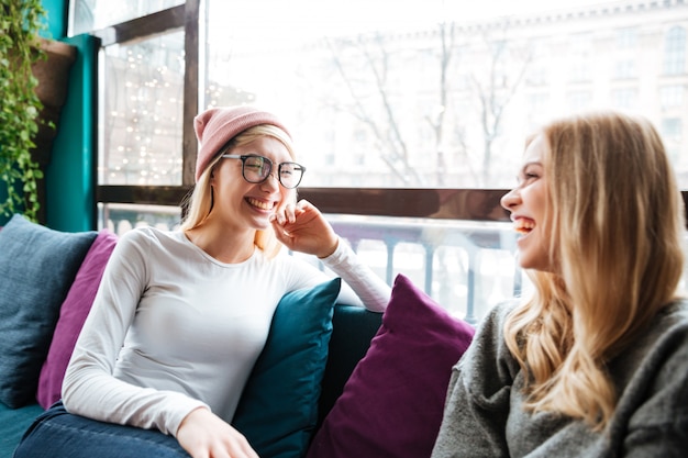 Zwei fröhliche Frauen, die im Café sprechen und lachen