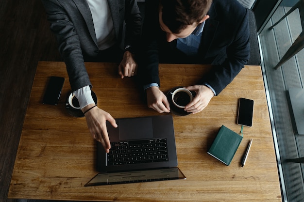 Zwei Geschäftsleute, die Laptop-Bildschirm während der Diskussion zeigen