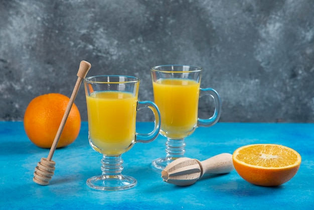 Zwei glasbecher orangensaft mit holzreibahle.