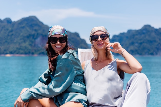 Zwei glückliche Blogger-Touristenfreunde in Seidenanzug und Schal und Sonnenbrille im Urlaub reisen um Thailand auf asiatischem Boot, Khao Sok Nationalpark.