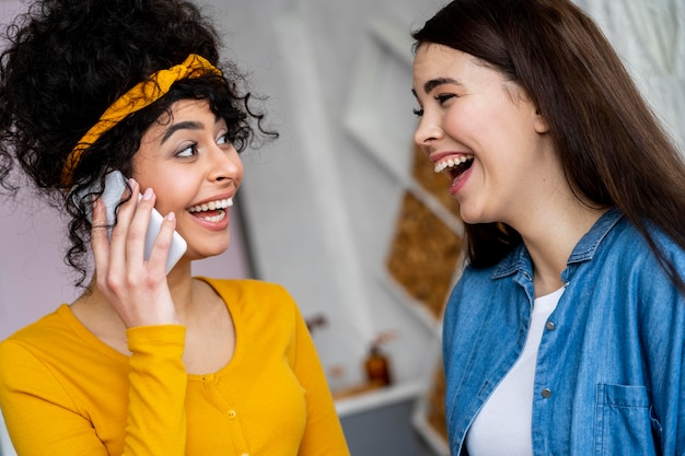 Zwei glückliche Frauen, die lächeln und am Telefon sprechen