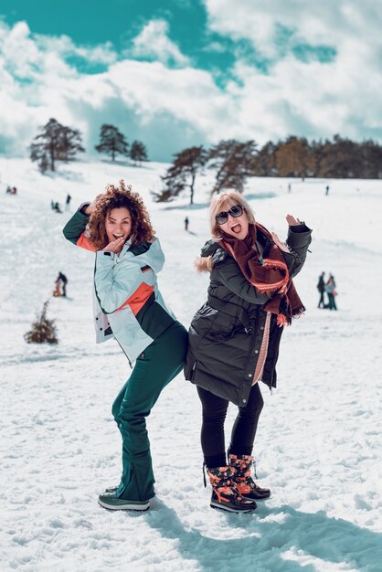 Zwei glückliche Frauen, die stehen und Spaß am Schnee haben