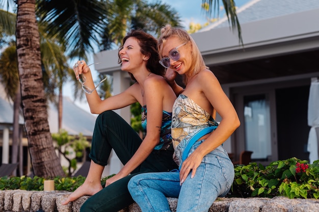 Zwei glückliche Freundinnen mit Sonnenbrille im Urlaub im tropischen Land