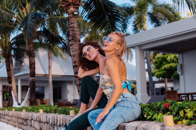 Zwei glückliche Freundinnen mit Sonnenbrille im Urlaub im tropischen Land