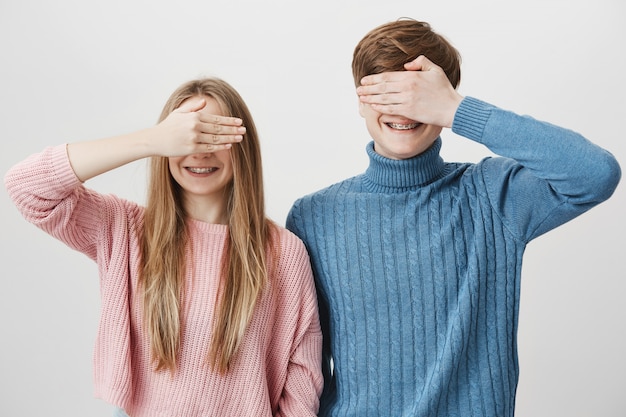 Zwei glückliche geschwister, die zusammen stehen, schließen mann und mädchen augen mit hand