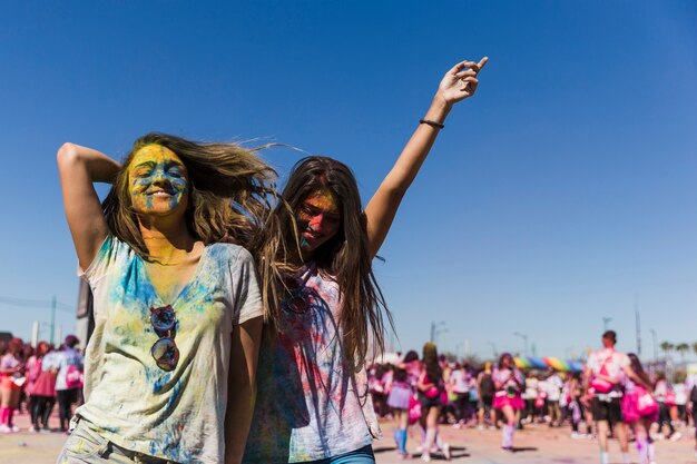 Zwei glückliche junge Frauen, die in das holi Festival genießen und tanzen