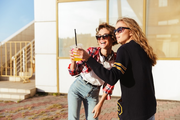 Zwei glückliche Teenager-Mädchen in der Sonnenbrille rösten