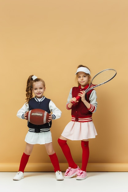 Zwei glückliche und schöne Kinder zeigen unterschiedliche Sportarten. Emotionskonzept.