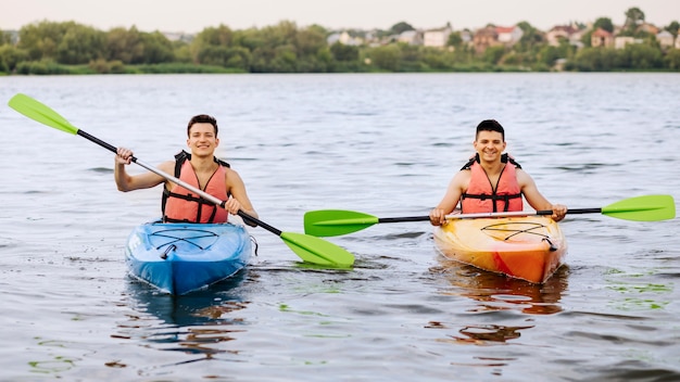 Zwei glücklicher Mann, der auf See Kayak fährt