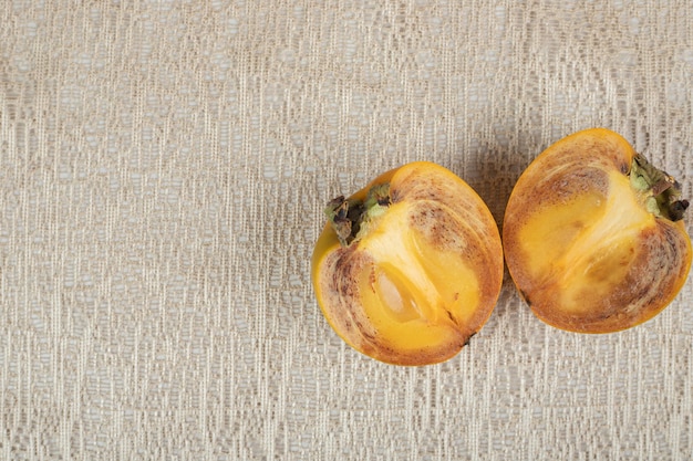 Kostenloses Foto zwei halb geschnittene kakisscheiben auf sackleinen