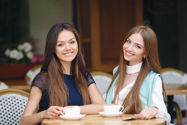 Zwei hübsche junge Frauen im Café mit Kaffee und Telefon
