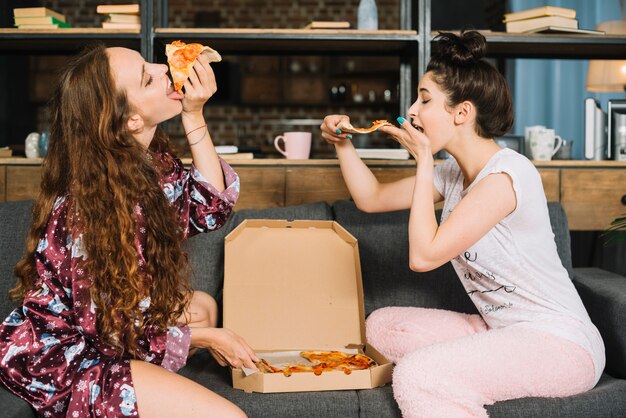 Zwei hungrige junge Frauen, die Pizza essen