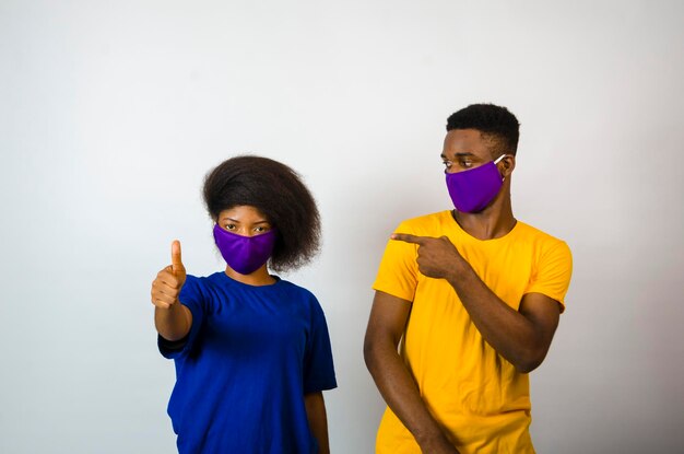 Zwei junge afrikanische studenten isoliert vor weißem hintergrund mit gesichtsmaske, um sich vor dem ausbruch in der gesellschaft zu schützen