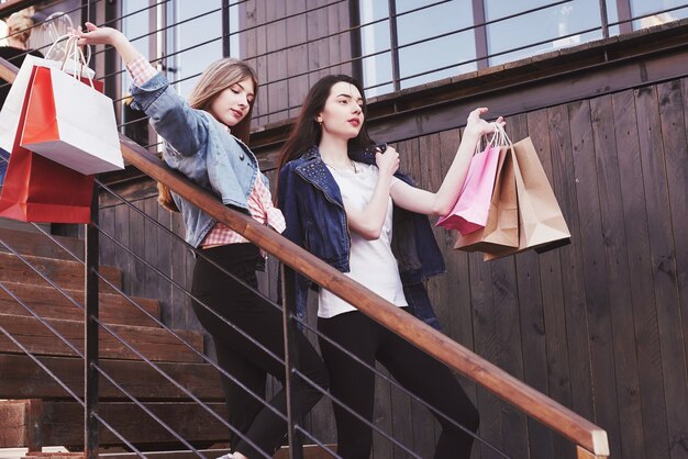 Zwei junge Frau, die Einkaufstaschen beim Gehen auf der Treppe nach dem Besuch der Geschäfte trägt.