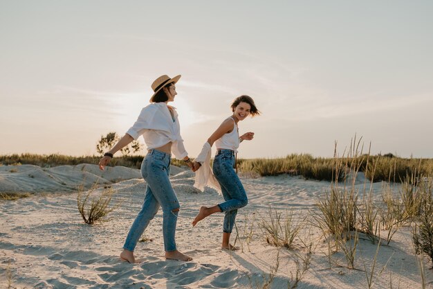 Zwei junge Frauen amüsieren sich am Strand bei Sonnenuntergang