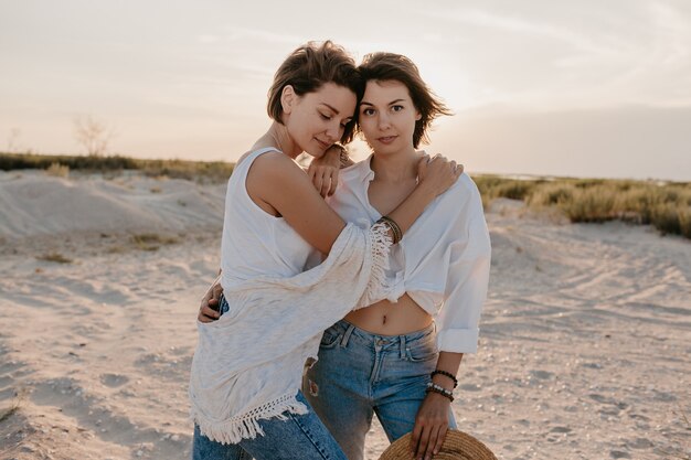 Zwei junge Frauen, die Spaß am Sonnenuntergangsstrand haben, schwule lesbische Liebesromantik