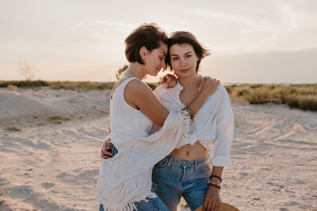 Zwei junge Frauen, die Spaß am Sonnenuntergangsstrand haben, schwule lesbische Liebesromantik