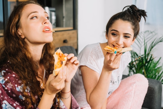 Zwei junge Frauen, die zu Hause Pizza essen