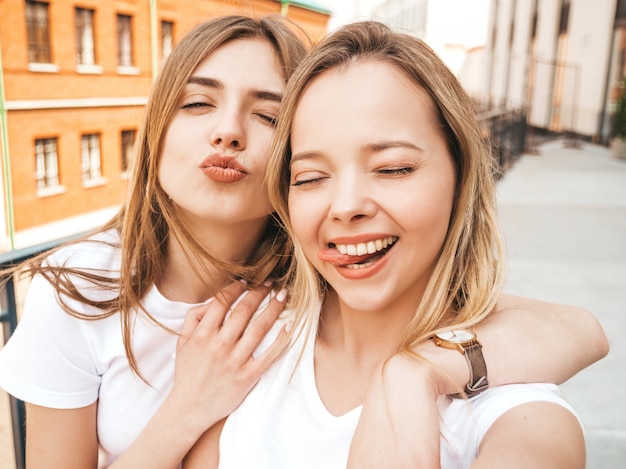 Zwei junge lächelnde blonde Frauen des Hippies in der Sommerkleidung. Mädchen, die selfie Selbstporträtfotos auf Smartphone machen. .