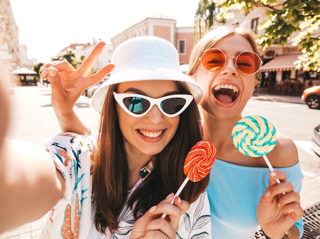 Zwei junge lächelnde Hippie-Frauen in der zufälligen Sommerkleidung.