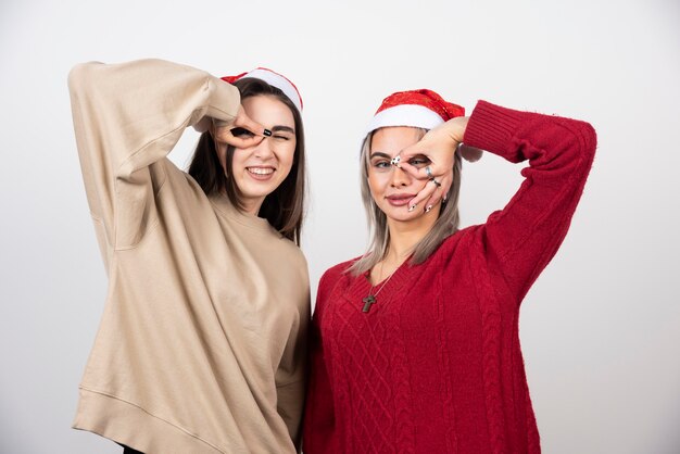 Zwei junge Mädchen in Santa Hut stehen und posieren.