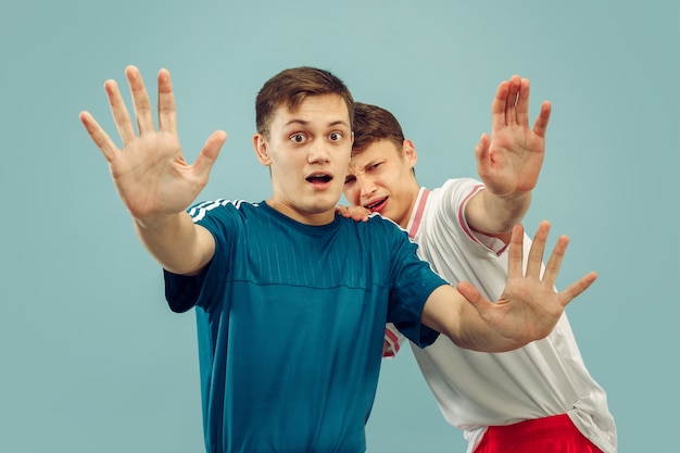 Zwei junge Männer, die in der Sportbekleidung stehen, isoliert. Fans von Sport, Fußball oder Fußballverein oder -mannschaft. Halbporträt der Freunde. Konzept menschlicher Emotionen, Gesichtsausdruck.