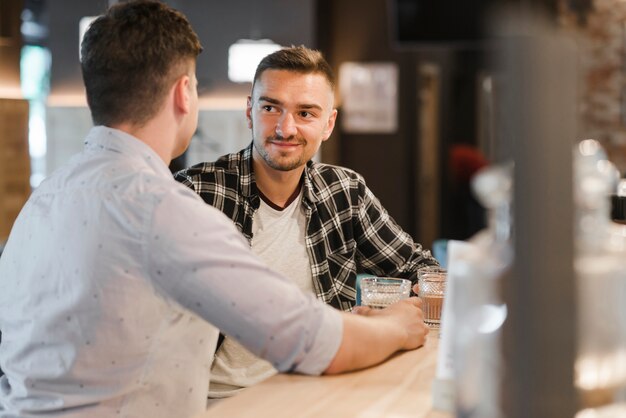 Zwei junge männliche Freunde, die Gläser des Getränks genießen