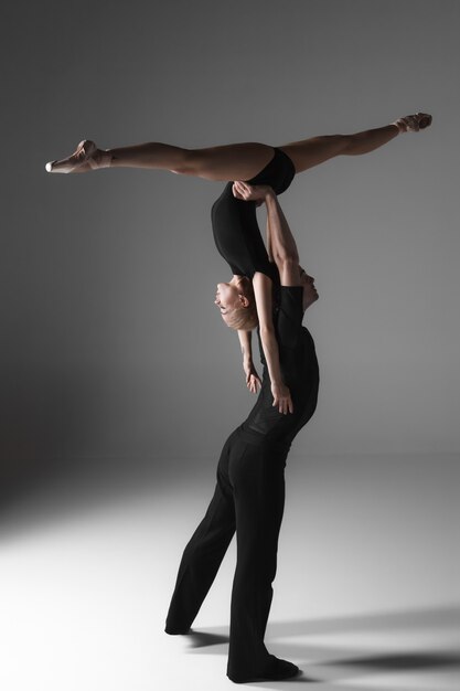 Zwei junge moderne Balletttänzer auf grauem Studiohintergrund