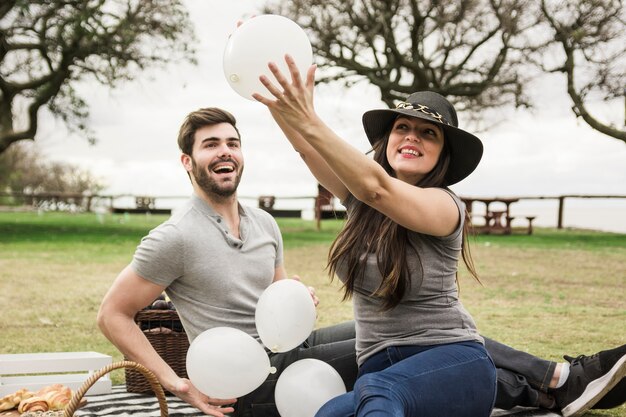 Zwei junge Paare, die mit weißen Ballonen im Park spielen