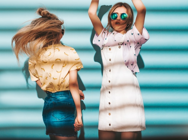 Kostenloses Foto zwei junge schöne lächelnde blonde hippie-mädchen im bunten t-shirt des modischen sommers kleidet.