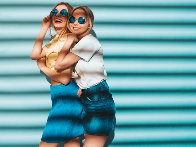 Zwei junge schöne lächelnde blonde Hippie-Mädchen im bunten T-Shirt des modischen Sommers kleidet.