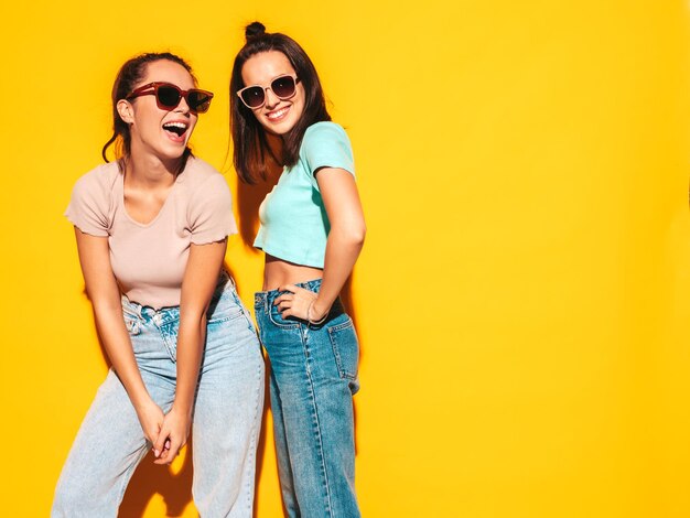 Zwei junge schöne lächelnde blonde Hipster-Frauen in trendiger Sommerkleidung Sexy unbeschwerte Frauen, die im Studio posieren Positive Models, die Spaß haben Fröhlich und glücklich