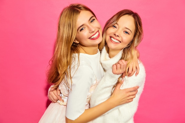 Zwei junge schöne lächelnde Frauen in den trendigen weißen Sommerkleidern