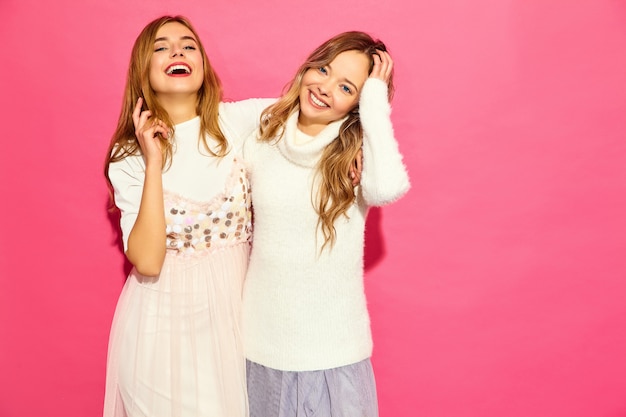 Zwei junge schöne lächelnde Frauen in den trendigen weißen Sommerkleidern